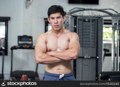 Strong Athletic Asian Man standing with crossed arms and looking at camera on gym,Muscular guy feeling so strong and healthy,Bodybuilder Concept