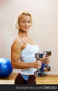 Strong beautiful woman lifting heavy dumbbells