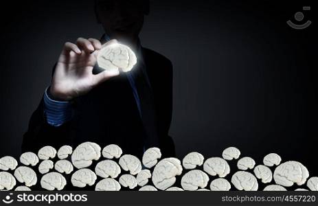 Strong creativity ability. Businessman on dark background taking with fingers brain icon