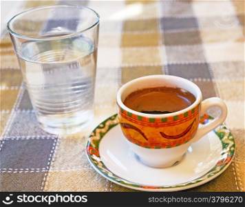 Strong Cypriot coffee with water water in a glass
