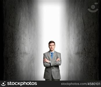 Strong enought to resist. Young confident businessman with hands crossed on chest between two walls