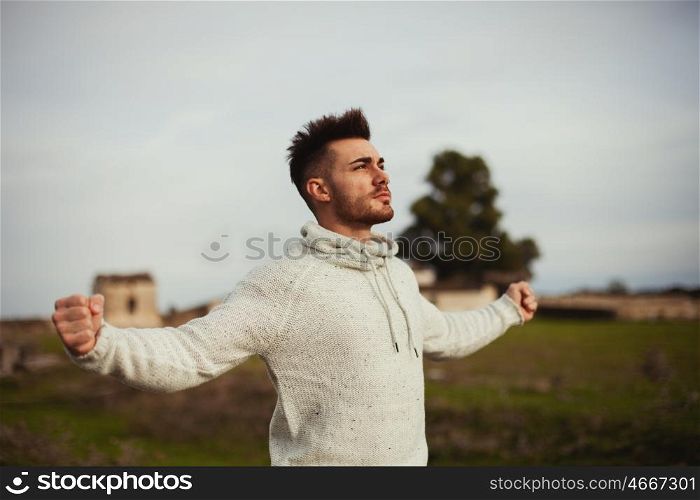 Strong guy open his arms in the meadow.