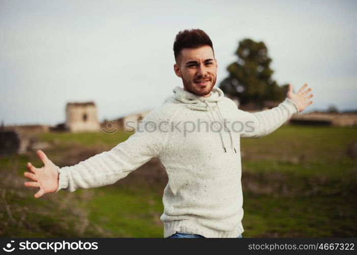 Strong guy open his arms in the meadow.