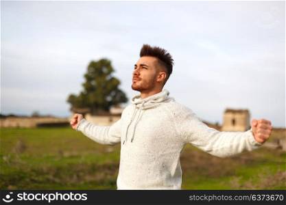Strong guy open his arms in the meadow.