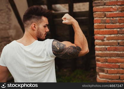Strong guy with a tattoo on his arm in al old house