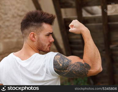 Strong guy with a tattoo on his arm in al old house