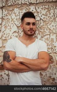 Strong guy with muscled arms with an old wall of background