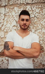 Strong guy with muscled arms with an old wall of background