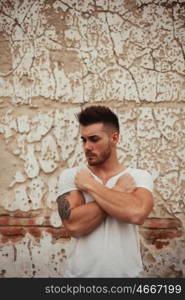 Strong guy with muscled arms with an old wall of background