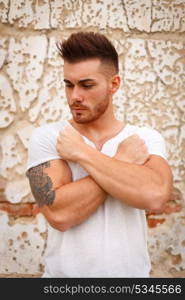 Strong guy with muscled arms with an old wall of background