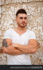 Strong guy with muscled arms with an old wall of background