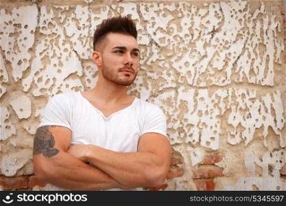 Strong guy with muscled arms with an old wall of background