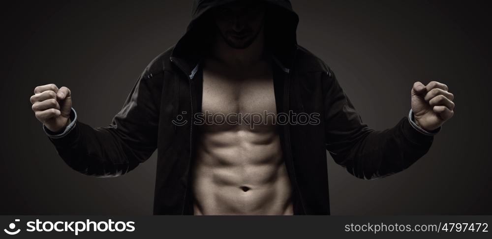 Strong hooded man making muscles