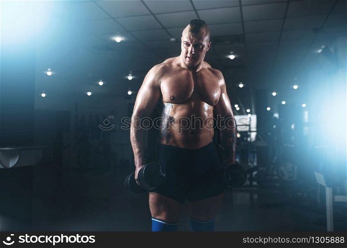Strong male bodybuilder with pancakes from barbell. Exercise with barbell in sport gym. Fitness training with weight. Bodybuilding workout. Strong male bodybuilder with pancakes from barbell