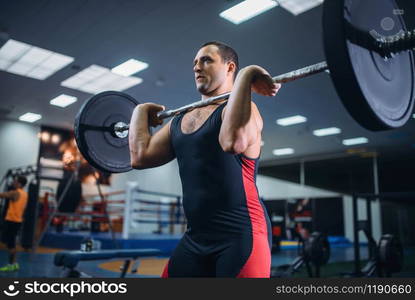 Strong male powerlifter doing deadlift a barbell in gym. Weightlifting workout, lifting training, athlete works with weight in the sport club. Strong powerlifter doing deadlift a barbell in gym