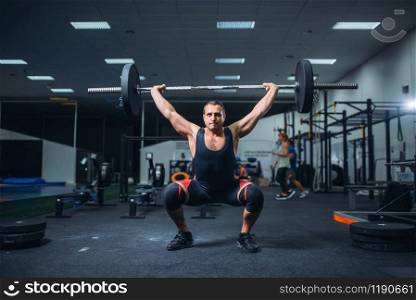 Strong male powerlifter doing deadlift a barbell in gym. Weightlifting workout, lifting training, athlete works with weight in sport club. Strong powerlifter doing deadlift a barbell in gym