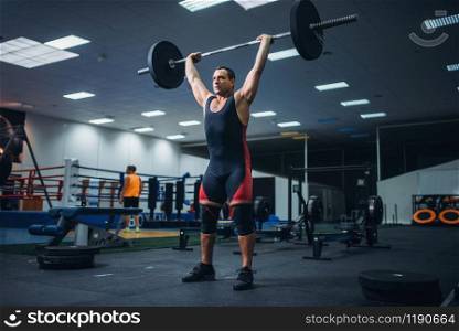 Strong male powerlifter doing deadlift a barbell in gym. Weightlifting workout, lifting training, athlete works with weight in the sport club. Strong powerlifter doing deadlift a barbell in gym