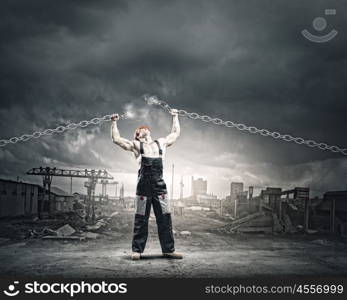 Strong man. Strong man in uniform tearing metal chain with hands