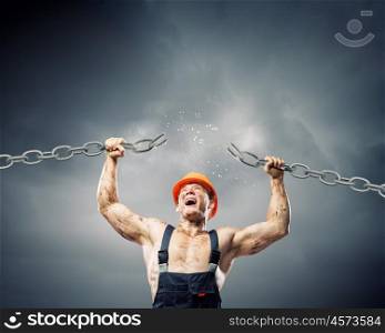 Strong man. Strong man in uniform tearing metal chain with hands