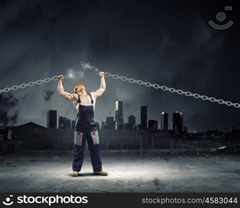 Strong man. Strong man in uniform tearing metal chain with hands