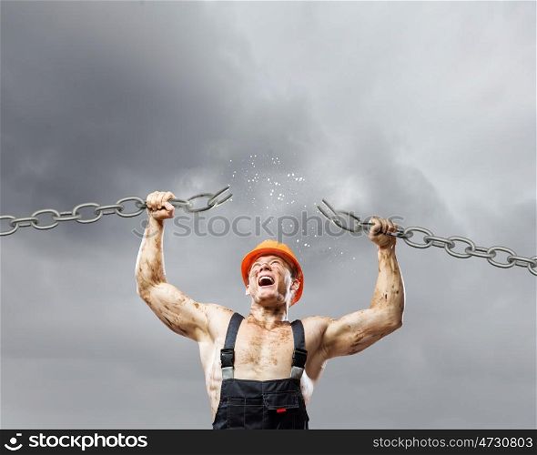 Strong man. Strong man in uniform tearing metal chain with hands