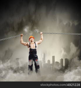 Strong man. Strong man in uniform tearing metal chain with hands