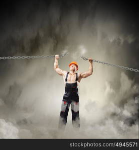 Strong man. Strong man in uniform tearing metal chain with hands