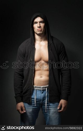 strong man wearing black hoodie isolated on dark background