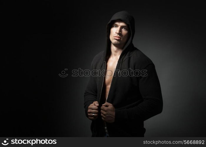 strong man wearing hoodie isolated on black background with copyspace