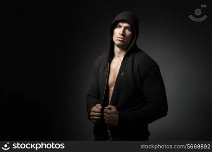 strong man wearing hoodie isolated on black background with copyspace