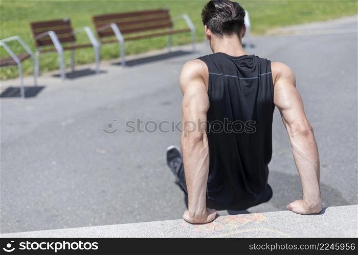 Strong man working out arms muscles doing triceps dips using bench.