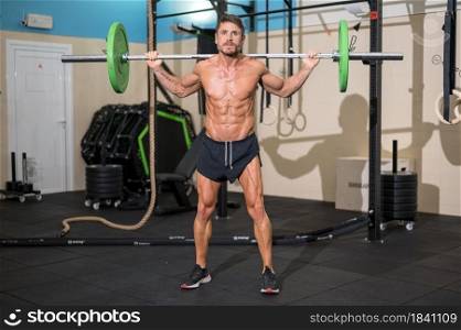 Strong men bodybuilder doing overhead with heavy barbell in modern gym. Functional training class. Bodybuilding and Fitness. High quality photo. Strong men bodybuilder doing overhead with heavy barbell in modern gym. Functional training class. Bodybuilding and Fitness