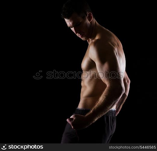 Strong muscular athlete posing on black