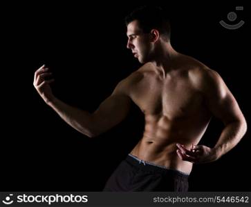 Strong muscular man gracefully posing on black