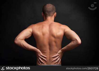 strong muscular man holding his naked back with hands - spine ache concept