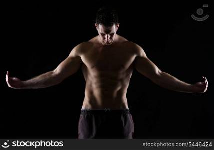 Strong muscular man posing on black