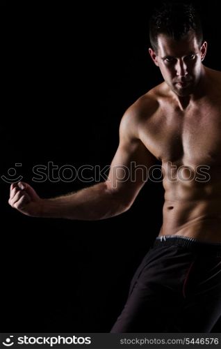 Strong muscular man posing on black