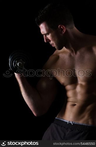 Strong muscular sports man rising dumbbell on black