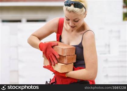 Strong pretty woman working on construction site, building house, installing bricks. Industrial work concept.. Woman working with bricks