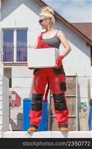 Strong pretty woman working on construction site, building house, installing gray airbricks. Industrial work concept.. Woman working with airbricks