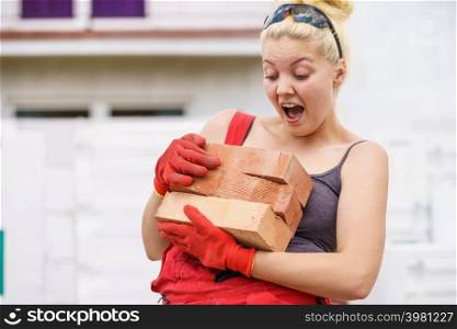 Strong pretty woman working on construction site, building house trying to carry heavy bricks, having fun laughing.. Funny woman carrying heavy bricks