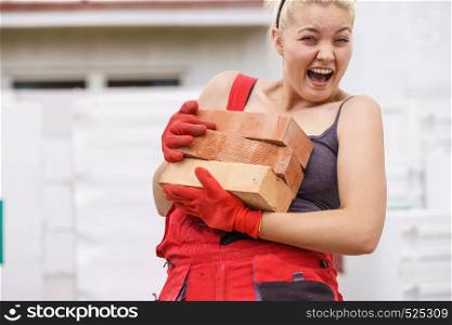 Strong pretty woman working on construction site, building house trying to carry heavy bricks, having fun laughing.. Funny woman carrying heavy bricks