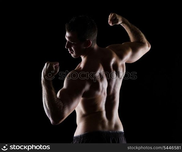 Strong sports man showing muscular back on black