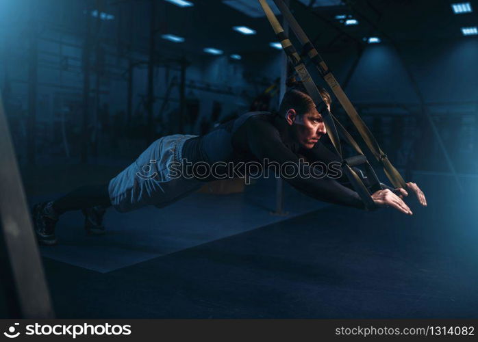 Strong sportsman on training, stretch endurance workout with ropes in gym. Energy exercises in sport club. Sportsman on training,endurance workout with ropes