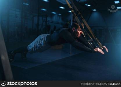 Strong sportsman on training, stretch endurance workout with ropes in gym. Energy exercises in sport club. Sportsman on training,endurance workout with ropes