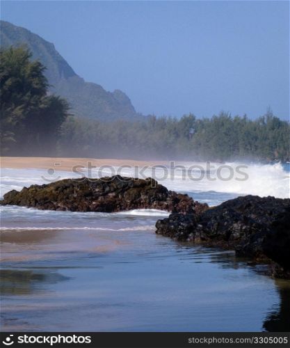 Strong waves crash over rocks on the beach at Lumahai on Kauai