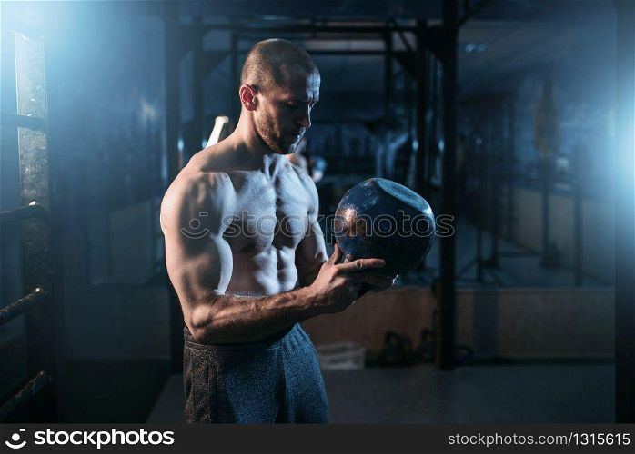Strong weightlifter workout with kettlebell in gym. Man with muscular torso training with weight