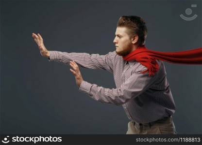 Strong wind blowing on man in red scarf, funny emotion. Powerful air flow blows on businessman face, black background