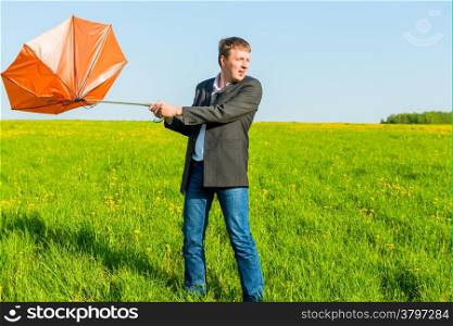 strong wind wrenched orange umbrella man