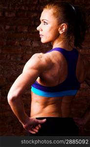 strong woman is posing against brick wall